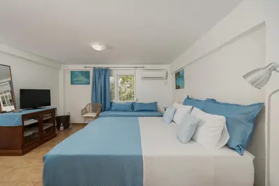a bedroom with a blue and white bed and a television at Stef's Place Porto Rafti in Porto Rafti