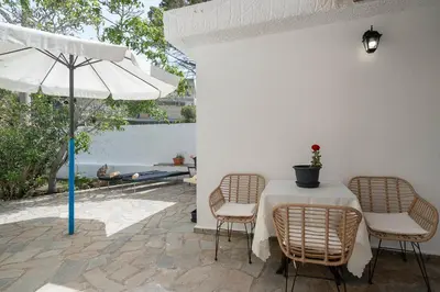 a table with chairs and an umbrella on a patio at Stef's Place Porto Rafti in Porto Rafti