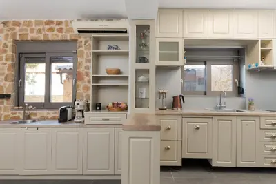 a kitchen with white cabinets and a stone wall at Aeolia Villa Athenian Riviera in Anavissos