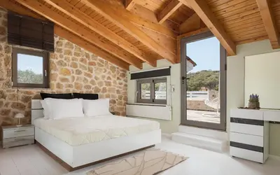 a bedroom with a white bed in a brick wall at Aeolia Villa Athenian Riviera in Anavissos