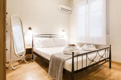 a bedroom with a bed and a mirror and a window at Restored Historic APT in Plaka,Under the Acropolis in Athens