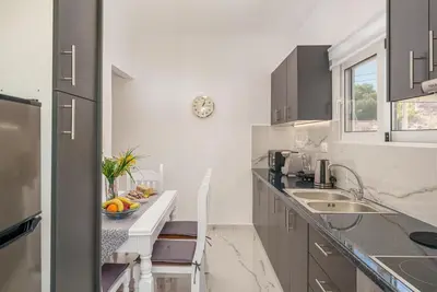 a white kitchen with a sink and a counter at Alexander Home in Vravrona