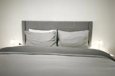 a large bed with white pillows and two lamps at Velora Apartments in Athens