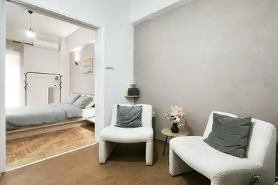 a bedroom with a bed and two chairs and a mirror at Velora Apartments in Athens