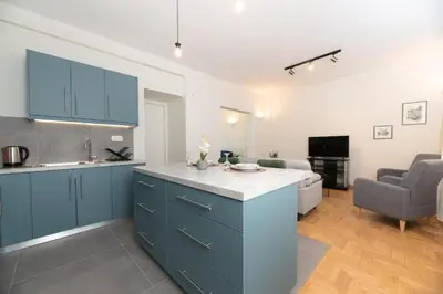 a kitchen with blue cabinets and a living room at 5th floor Apt with Acropolis view in Pangrati in Athens