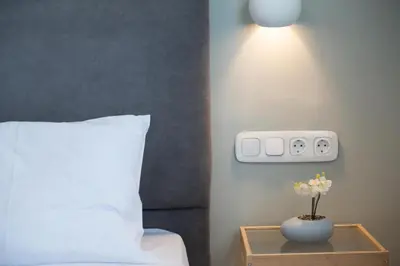 a bedroom with a bed and a vase with flowers on a table at 5th floor Apt with Acropolis view in Pangrati in Athens