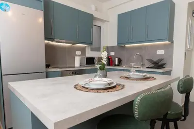 a kitchen with blue cabinets and a counter with two sinks at 5th floor Apt with Acropolis view in Pangrati in Athens