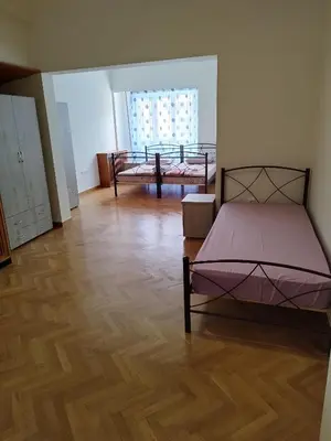 a bedroom with two beds and a wooden floor at Triple room in Athens