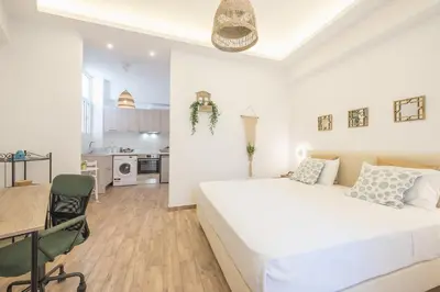 a white bedroom with a bed and a kitchen at Ble Elia Parthenon Suite in Athens