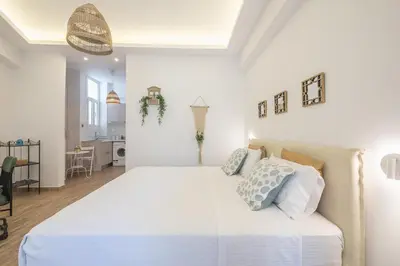a white bedroom with a large bed with blue pillows at Ble Elia Parthenon Suite in Athens