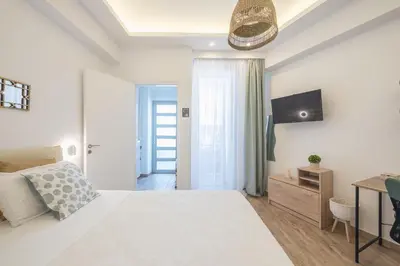 a white bedroom with a bed and a tv at Ble Elia Parthenon Suite in Athens
