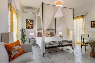 a bedroom with a canopy bed and a couch at Mira Seaside Residence in Kalívia Thorikoú