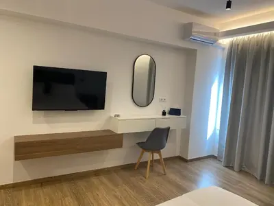 a room with a tv and a chair and a mirror at Real City Suites Lekka in Athens