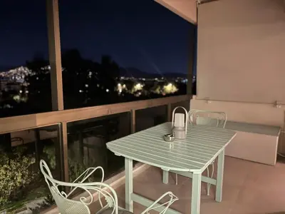 a green table and chairs on a balcony with a view at Nomadic life-Elegant Apartment by Athens Riviera in Athens