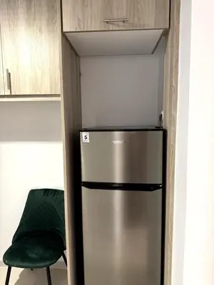 a stainless steel refrigerator in a kitchen with a green chair at Athenian Stay Chara's 2 Apartment in Athens