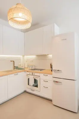 a kitchen with white cabinets and a white refrigerator at Vouliagmeni Suite 1 by Anothr in Athens