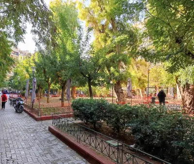 a park with trees and a motorcycle on a sidewalk at ARIS Ampelokipoi retreat in Athens
