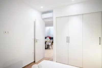 a white bedroom with white cabinets and a table at Exclusive 3-Bedroom Haven in Kolonaki Center in Athens