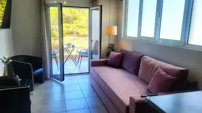 a living room with a purple couch and a patio at Spacious Modern apartment in Palaiá Fókaia