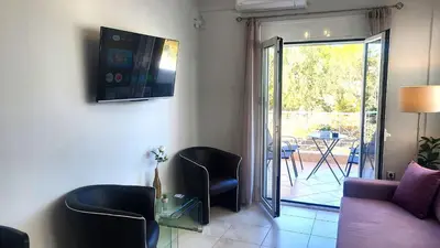 a living room with a couch and chairs and a patio at Spacious Modern apartment in Palaiá Fókaia
