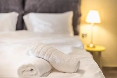 a pile of white towels sitting on a bed at Modern Apartment - Balcony & Metro Access in Athens