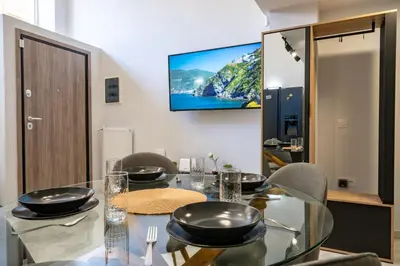a dining room with a glass table with a television on the wall at LEX & LUX 3-Levels Maisonette in Athens