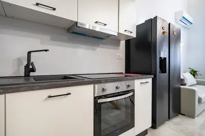 a kitchen with white cabinets and a stainless steel refrigerator at LEX & LUX 3-Levels Maisonette in Athens