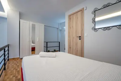 a white bedroom with a bed and a mirror at LEX & LUX 3-Levels Maisonette in Athens