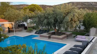 a pool with chairs and a tree next to a house at VillaSophycom in Vari