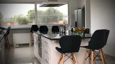 a kitchen with black bar stools and a large window at VillaSophycom in Vari
