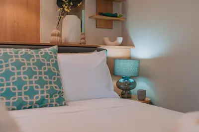 a bed with a pillow and a lamp on a table at Koukaki Zen Studio in Athens