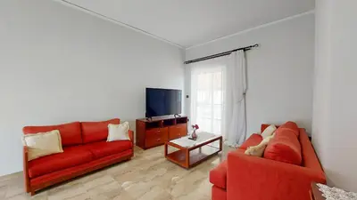 a living room with a red couch and a tv at Modern, Renovated Apartment in Nikaia in Piraeus