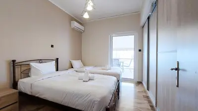 a bedroom with two beds with white sheets and a window at Modern, Renovated Apartment in Nikaia in Piraeus