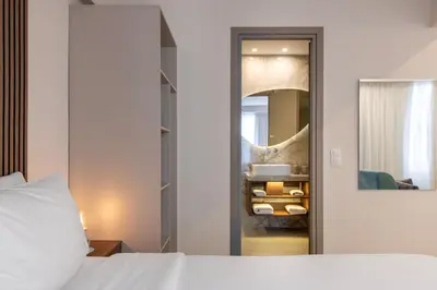 a bedroom with a white bed and a mirror at Ermou Kaliendia Suite in Athens