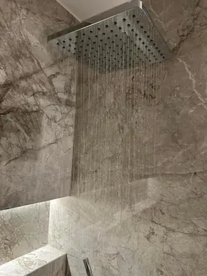 a shower in a bathroom with a stone wall at Ermou Kaliendia Suite in Athens