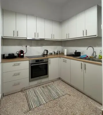 a kitchen with white cabinets and a stove top oven at Cozy & Fully renovated apartment in Athens