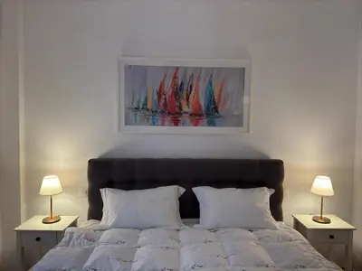 a bedroom with a bed with two lamps and a painting at Cozy & Fully renovated apartment in Athens