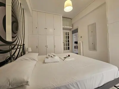 a white bedroom with a large bed with two pairs of scissors at SantaRoza Luxury Apartment in Piraeus
