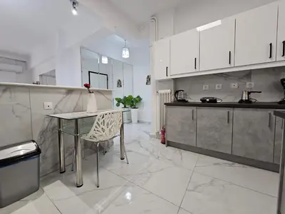a kitchen with white cabinets and a table and chairs at SantaRoza Luxury Apartment in Piraeus