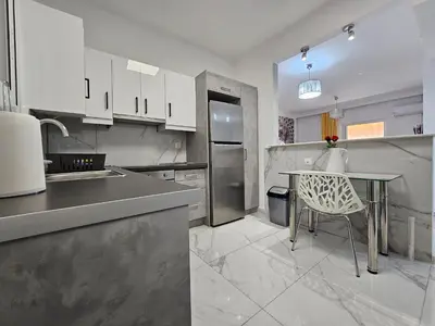 a kitchen with a table and a stainless steel refrigerator at SantaRoza Luxury Apartment in Piraeus