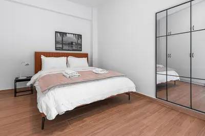 a white bedroom with a large bed and a mirror at Koukaki 2BR Apt with Balcony, Walk to Acropolis in Athens