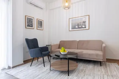 a living room with a couch and a table and a chair at Koukaki 2BR Apt with Balcony, Walk to Acropolis in Athens