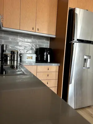 a kitchen with a stainless steel refrigerator and wooden cabinets at Altitude 5 Penthouse Elliniko in Athens