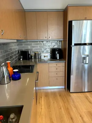 a kitchen with a stainless steel refrigerator and wooden cabinets at Altitude 5 Penthouse Elliniko in Athens