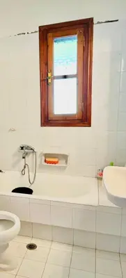 a bathroom with a tub and a toilet and a window at Lagonisi2025 in Kalívia Thorikoú