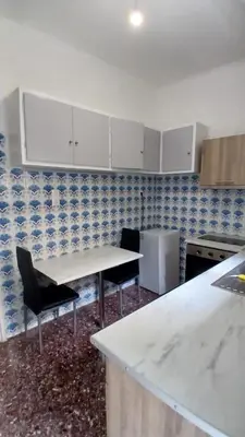 a kitchen with white cabinets and a table and chairs at Cozy and totally sunny apartment in Athens