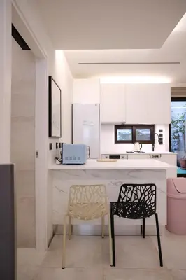 a kitchen with white cabinets and a chair and a counter at Lime house in Athens