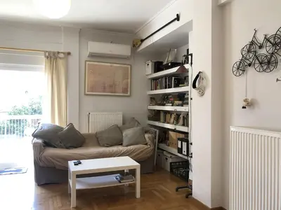 a living room with a couch and a book shelf at Quiet, central, on airport metro and bus line in Athens