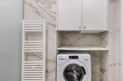 a washing machine in a bathroom with white cabinets at Attica - Captivating 2-Bedroom Apt & Balcony in Athens in Athens