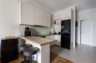 a kitchen with white cabinets and a counter with stools at Attica - Captivating 2-Bedroom Apt & Balcony in Athens in Athens